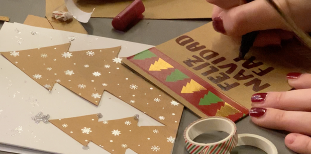 Participant décorant une carte de Noël avec dessins, lettrage et éléments de collage