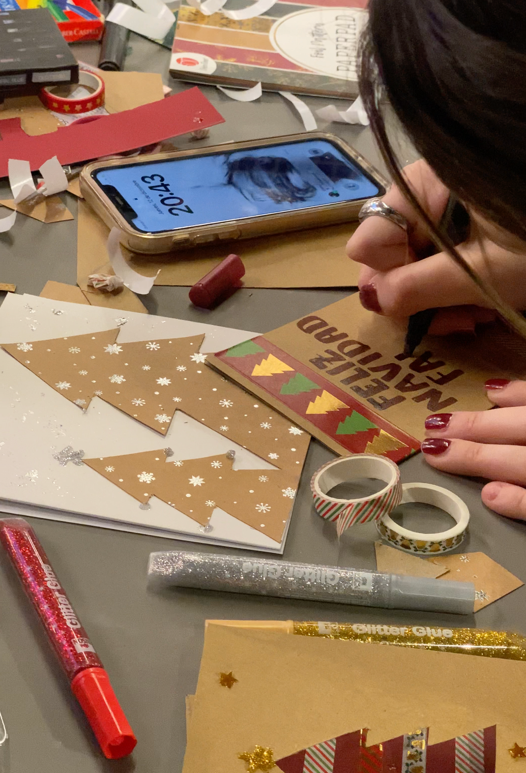 Participant décorant une carte de Noël avec dessins, lettrage et éléments de collage