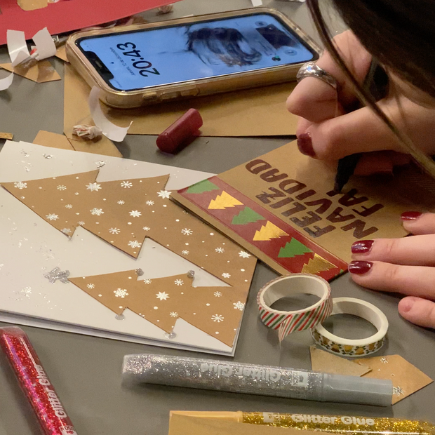 Participant décorant une carte de Noël avec dessins, lettrage et éléments de collage