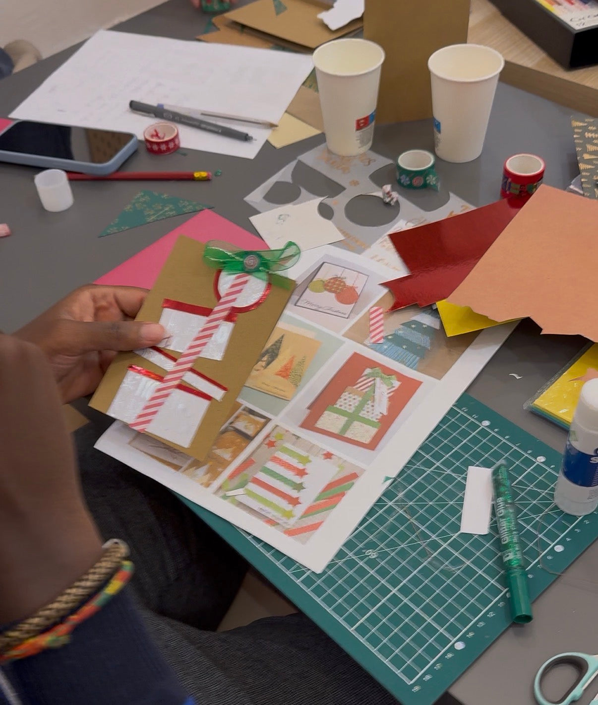 Table d’atelier avec papiers colorés, feutres et matériaux pour fabriquer des cartes de Noël