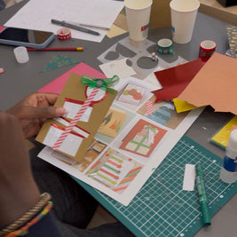 Table d’atelier avec papiers colorés, feutres et matériaux pour fabriquer des cartes de Noël
