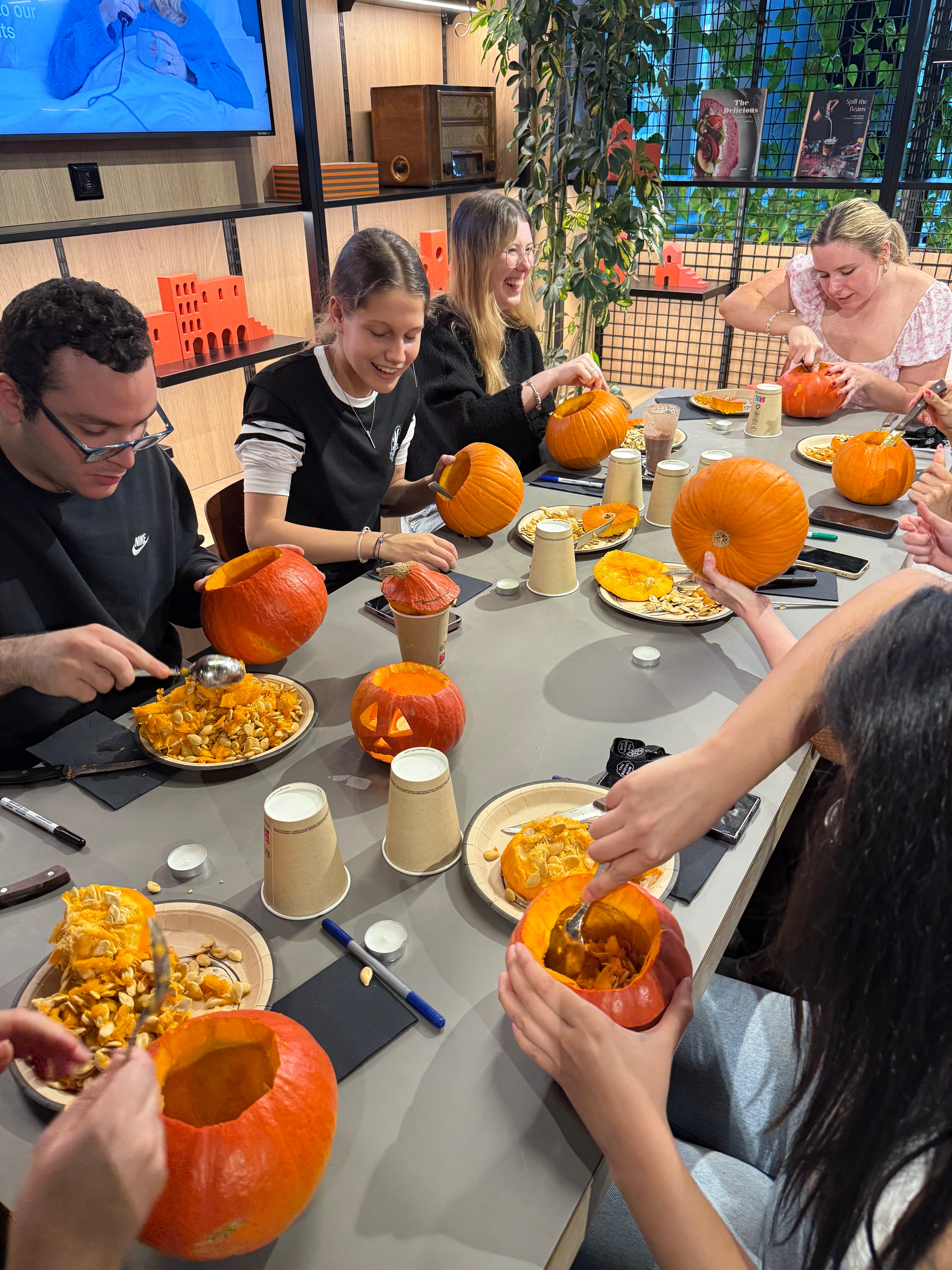 Table d’atelier avec citrouilles, outils et décorations pour créer des lanternes d’Halloween