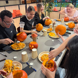 Table d’atelier avec citrouilles, outils et décorations pour créer des lanternes d’Halloween