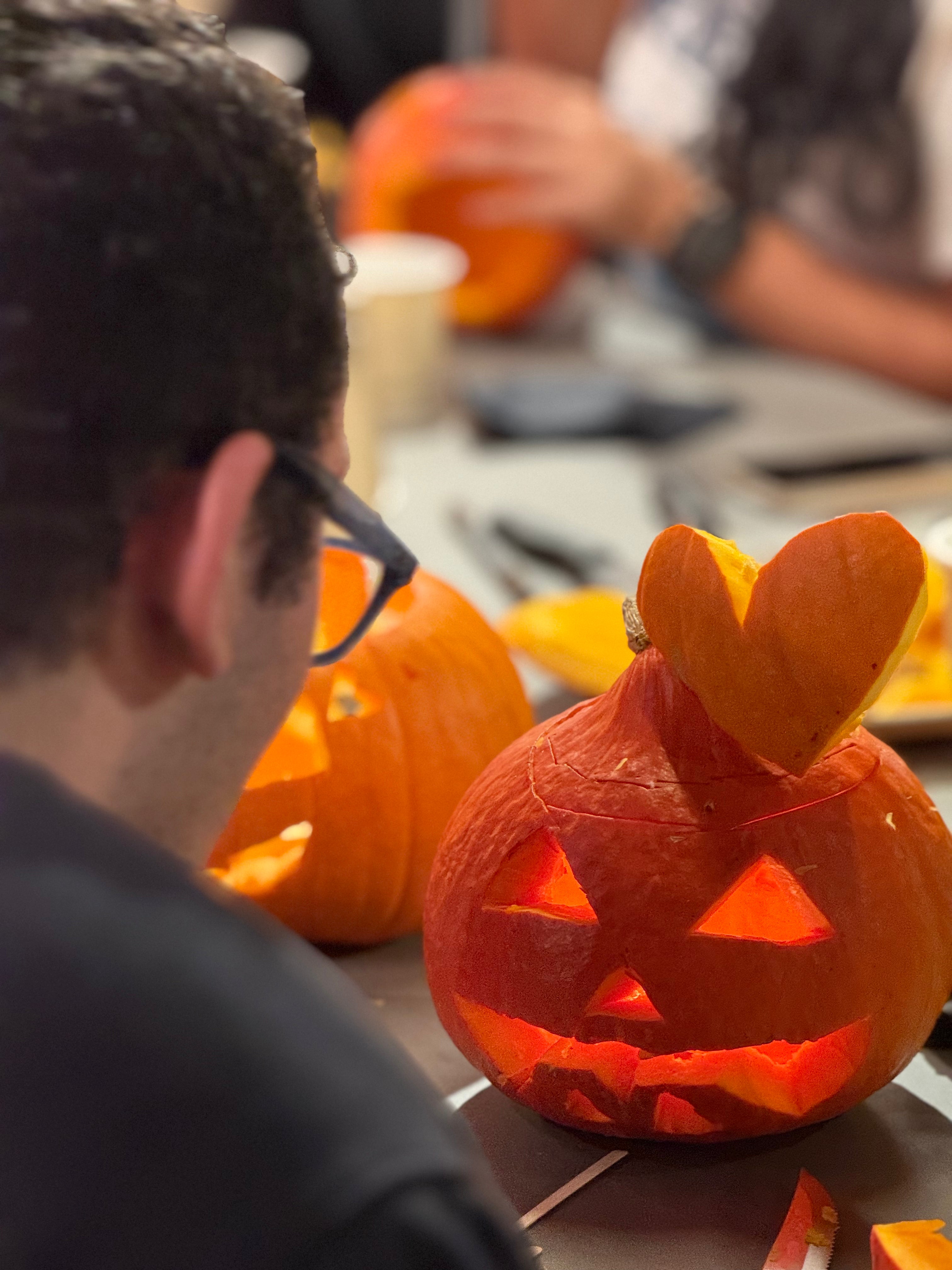 Enfant décorant une citrouille avec l’aide d’un adulte pendant un atelier créatif d’Halloween