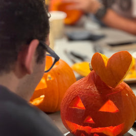 Enfant décorant une citrouille avec l’aide d’un adulte pendant un atelier créatif d’Halloween
